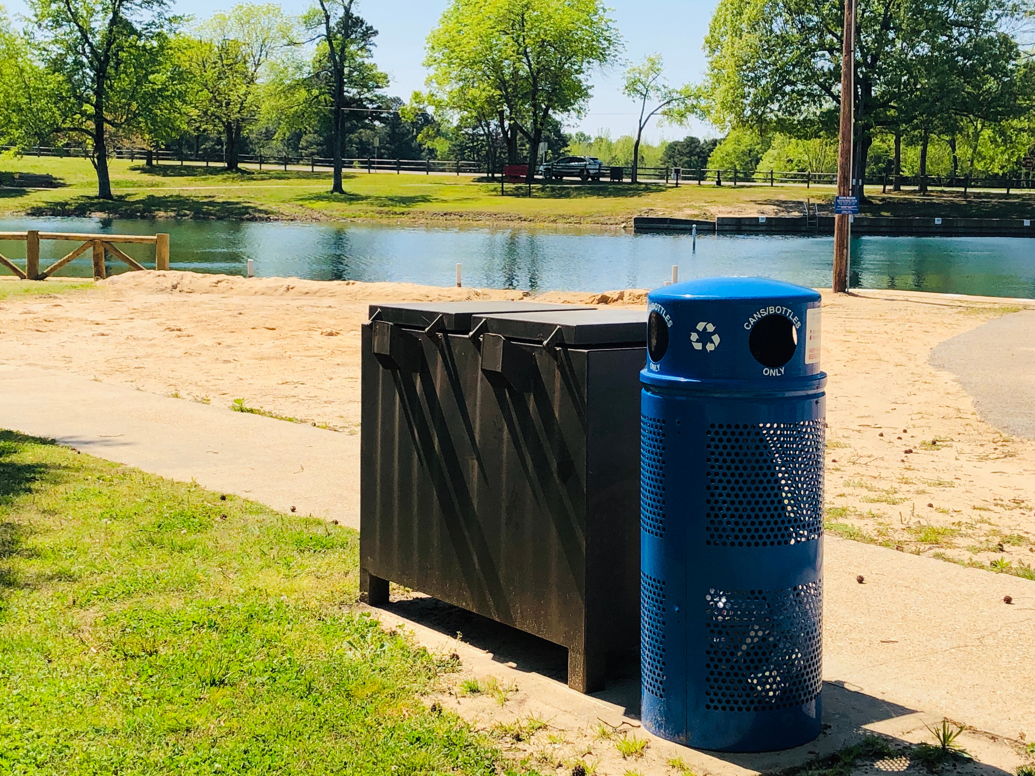nother blue, metal recycling bin in the foreground with Lake Ponder swim beach in the background 
